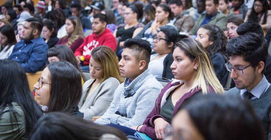 A close up image of a body of students in class listening to a speaker.